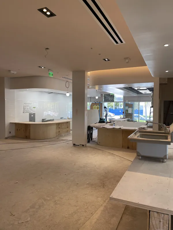 Commercial interior with service counters and a linear ceiling diffuser during construction