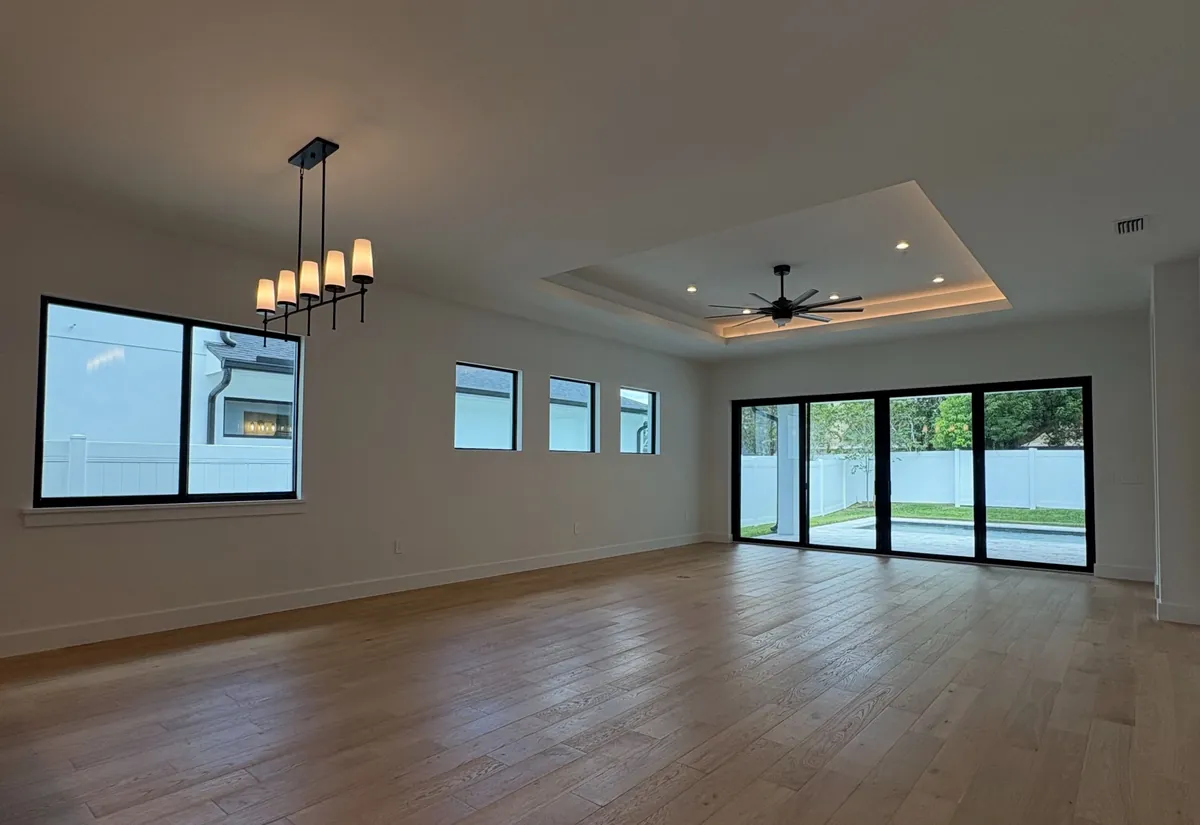 Design inspiration from another Florida home: open living and dining room with a tray ceiling and black framed sliding doors