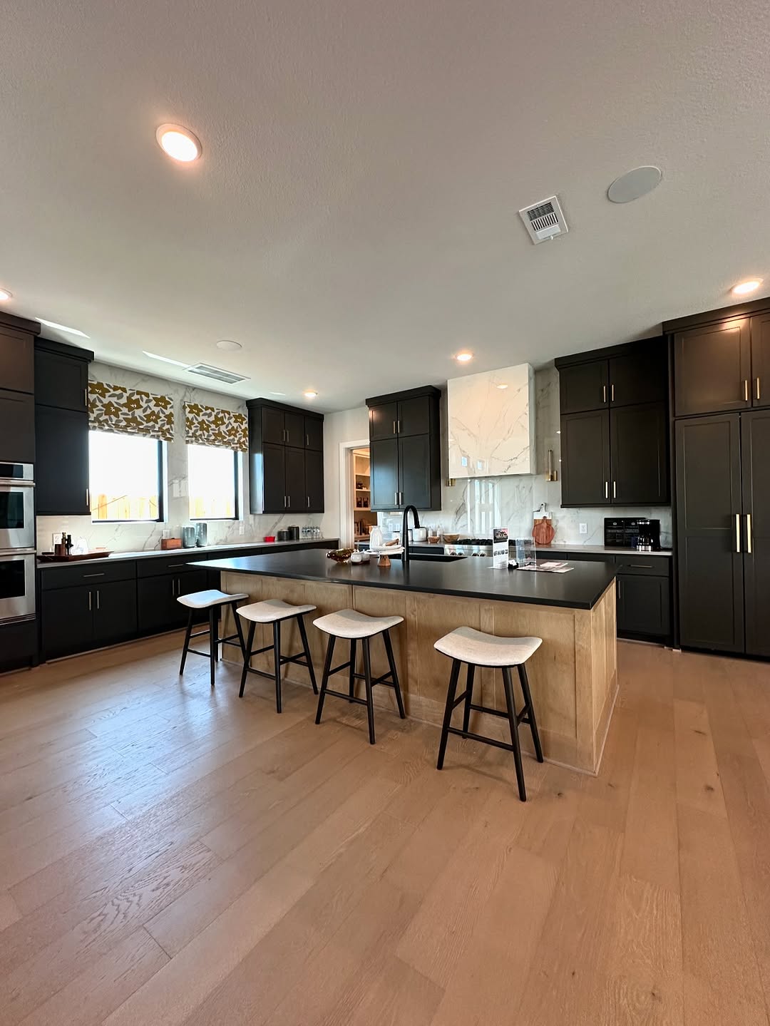 Gourmet kitchen with dark cabinets, marble backsplash, and large island