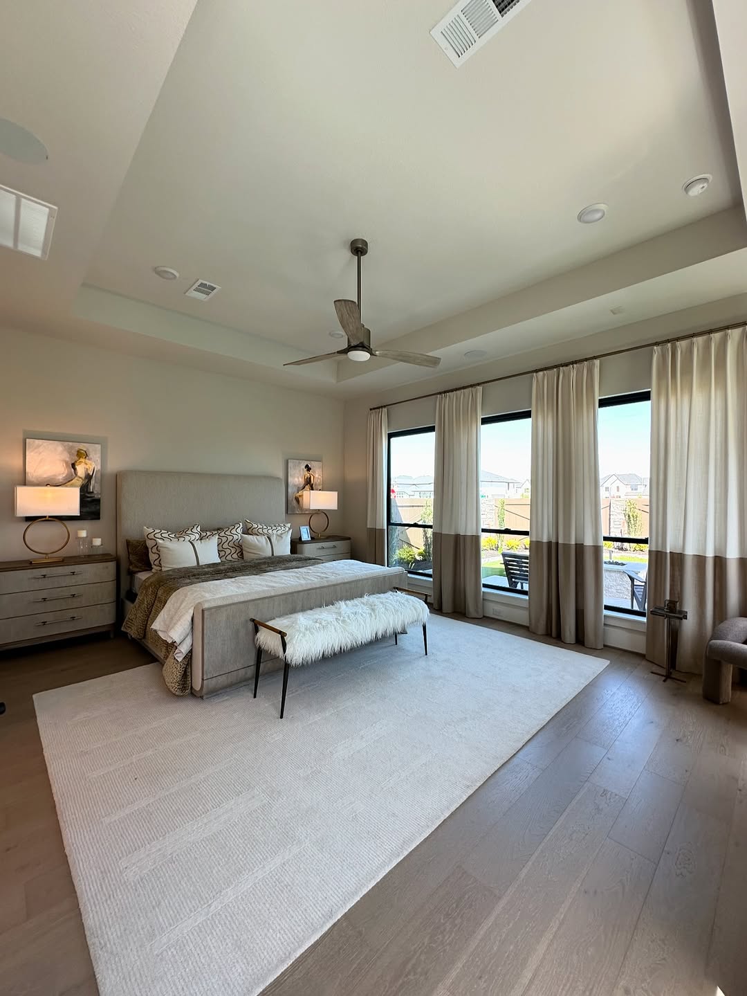 Master bedroom with neutral palette, ceiling fan, and large windows