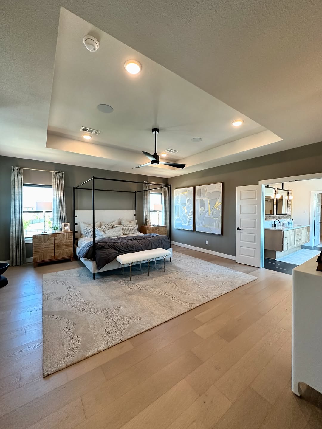 Master bedroom with tray ceiling, canopy bed frame, and wood accents