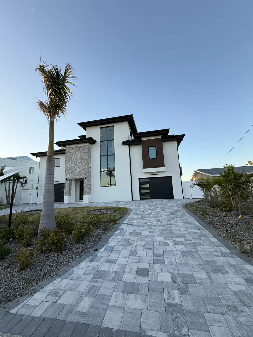 Modern two story stucco home with a stone accent and a paver driveway in Florida