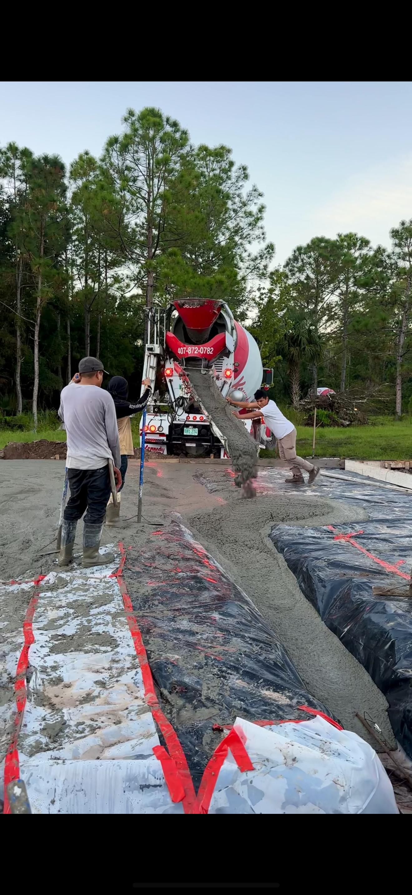 Construction crew leveling a concrete slab for a custom home