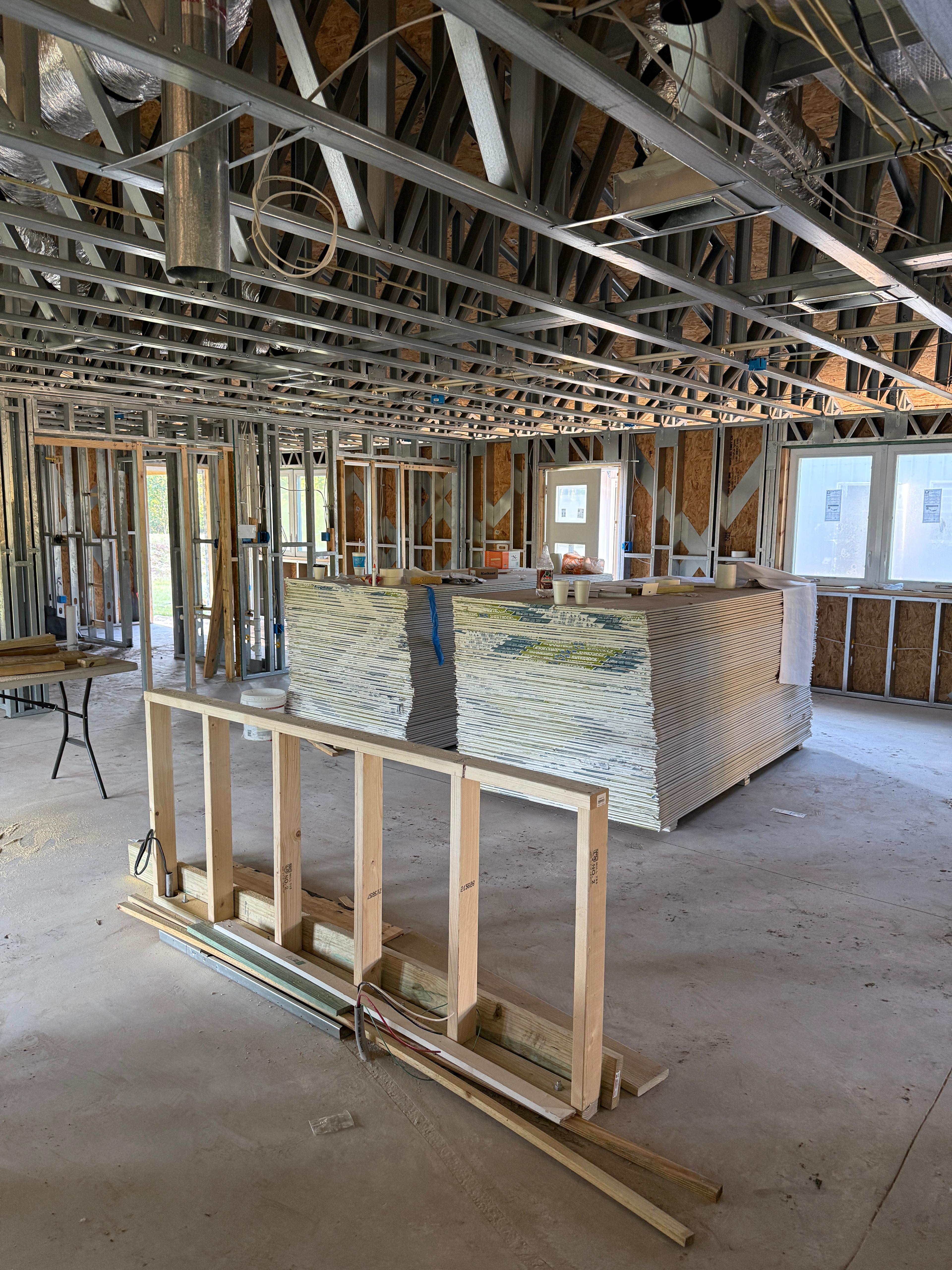 Steel framing with drywall sheets staged for installation