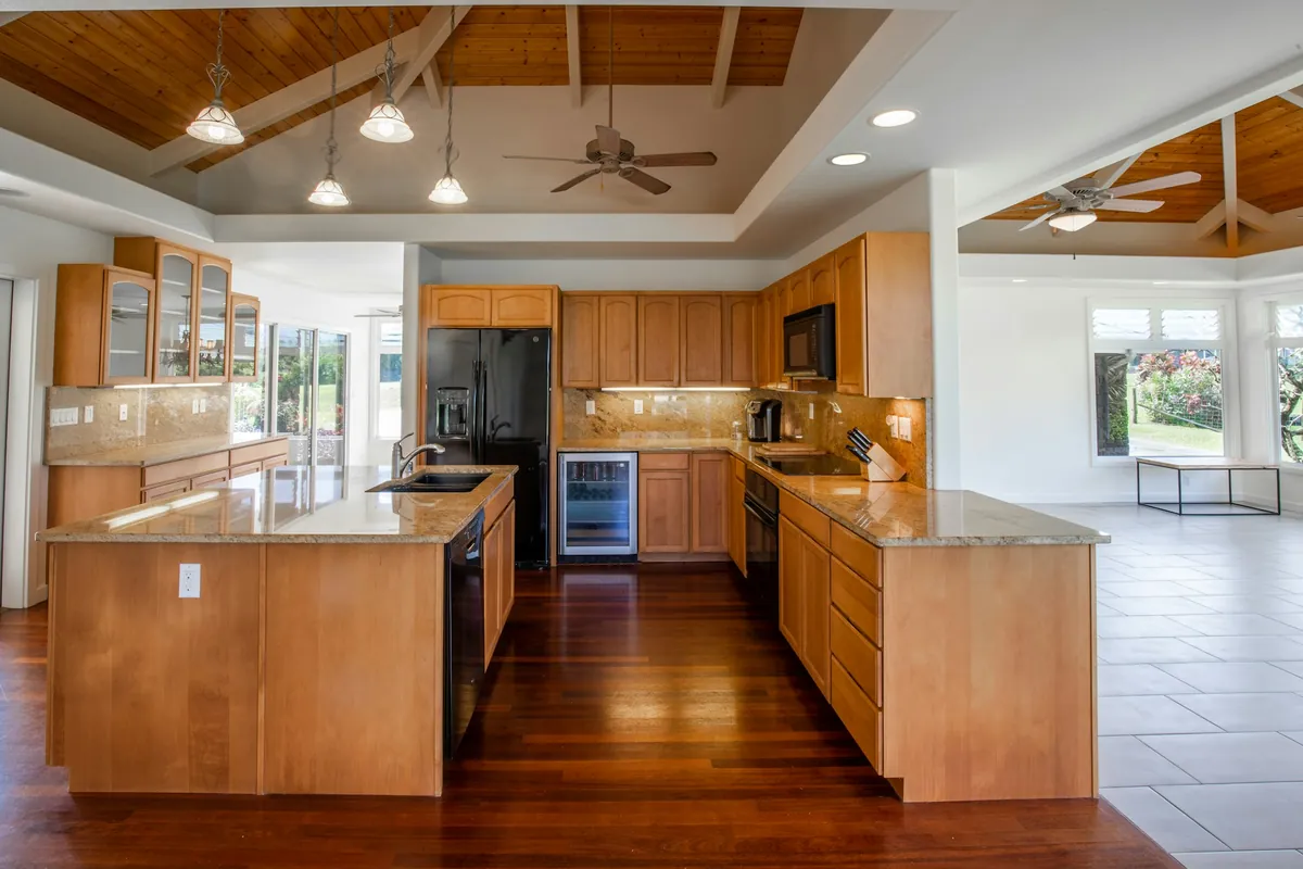 Natural wood cabinets and island in an open kitchen with a wood plank ceiling