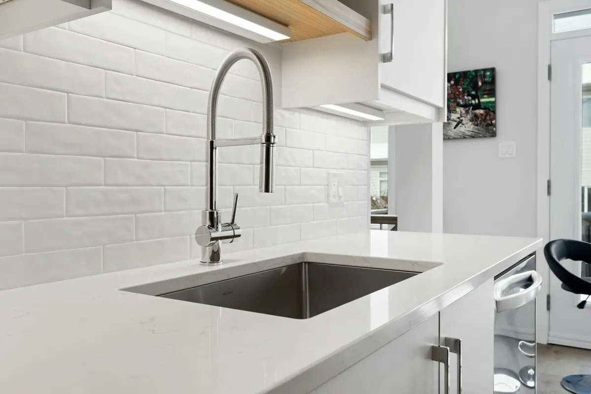 Bright white countertop with an undermount sink and a tall chrome faucet