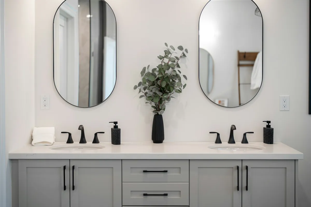 Double vanity with two sinks, oval mirrors and black faucets