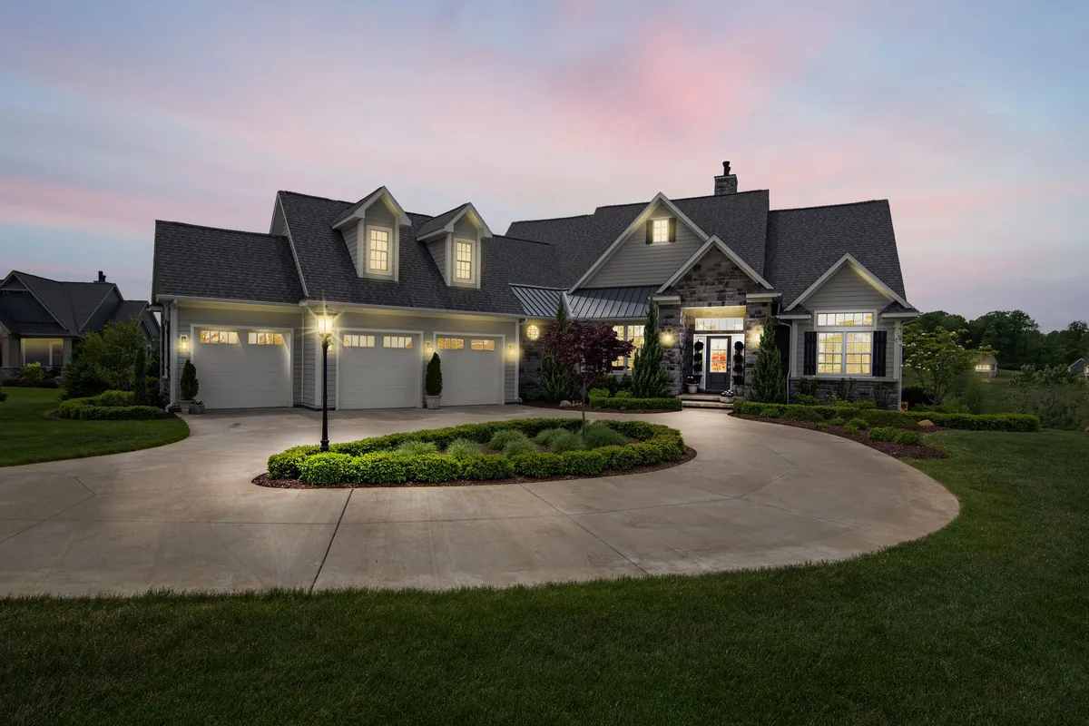 House at dusk with lit coach lights, a lamp post and glowing windows