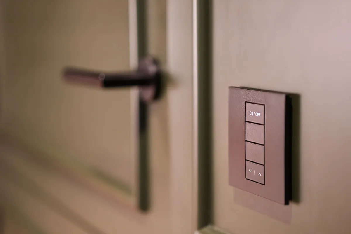 Smart keypad light switch with on, off and dimming buttons beside a door
